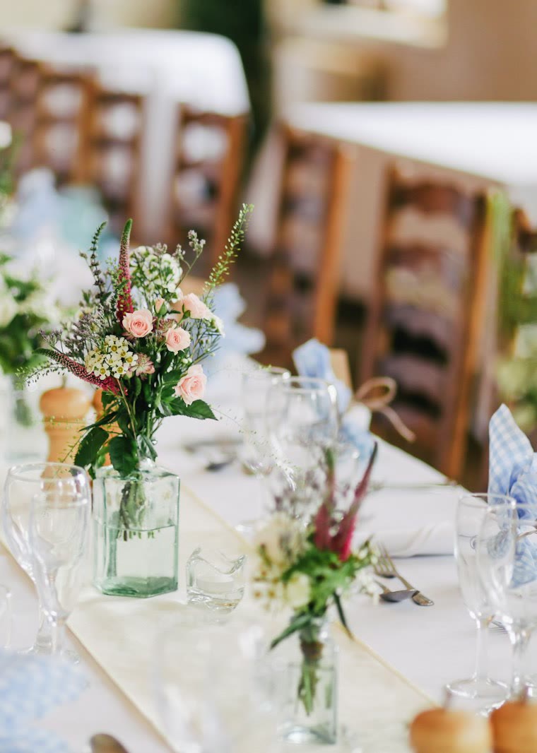 Mesa larga con copas, servilletas y flores