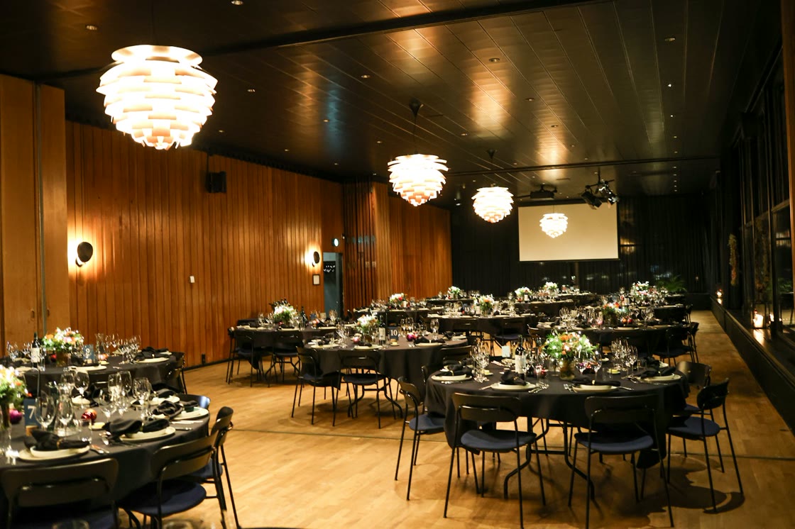 Salón iluminado con mesas redondas listas para la fiesta